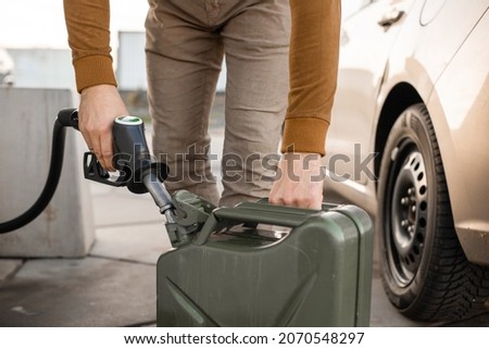 Man refilling canister with fuel on the petrol station. Close up view. Gasoline, diesel is getting more expensive.