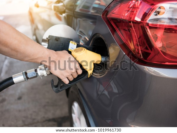 Man refilling gasoline oil with fuel at the\
refuel station