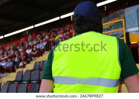 Man with reflective jacket while checking the audience in the stands of the packed stadium during the event