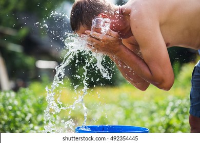 Man Refreshes Himself With A Splash Of Cool, Fresh Water On His Face.