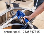 Man refueling boat at marina. Gas pump nozzle filling pontoon party boat fuel tank.