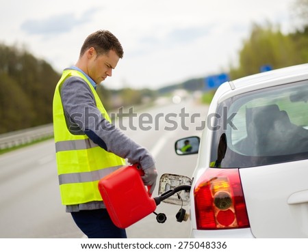Man refuelling her car on a highway roadside 