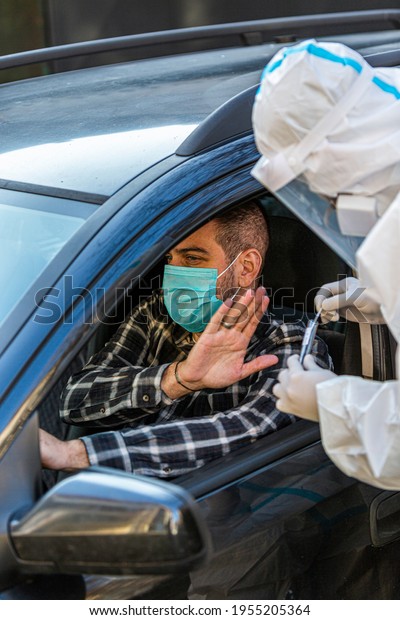 Man refuses\
medical worker trying to perform drive-thru COVID-19 test, taking\
nasal swab sample from patient through car window, PCR diagnostic,\
doctor in PPE holding test kit.\

