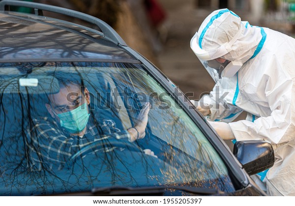 Man refuses\
medical worker trying to perform drive-thru COVID-19 test, taking\
nasal swab sample from patient through car window, PCR diagnostic,\
doctor in PPE holding test\
kit.