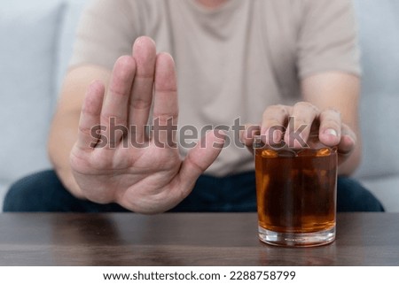 man refuses say no and avoid to drink an alcohol whiskey , stopping hand sign male, alcoholism treatment, alcohol addiction, quit booze, Stop Drinking Alcohol. Refuse Glass liquor, unhealthy, reject