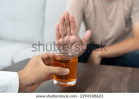 man refuses say no and avoid to drink an alcohol whiskey , stopping hand sign male, alcoholism treatment, alcohol addiction, quit booze, Stop Drinking Alcohol. Refuse Glass liquor, unhealthy, reject