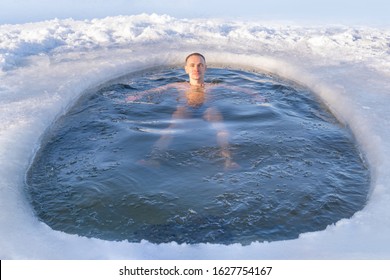 A Man Relaxes While Swimming In A Cold Hole In Ice Water In Winter