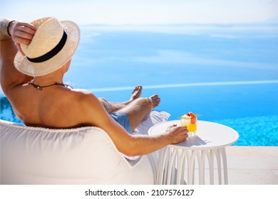 Man relaxing by infinity pool with beautiful sea view - Powered by Shutterstock