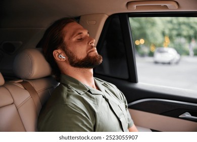 Man relaxing in a car, wearing wireless earbuds, eyes closed, peaceful expression, soft interior lighting - Powered by Shutterstock