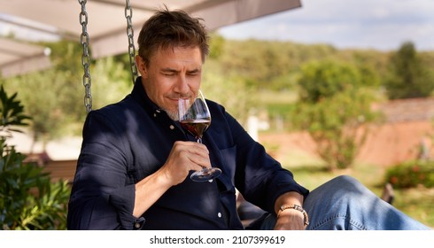 Man relaxing drinking tasting red wine outdoor in garden. Authentic and atmospheric moment. - Powered by Shutterstock
