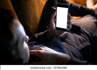 Man relaxing during listening to the music while lying on sofa - blank screen smartphone