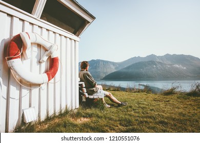 Man Relaxing Enjoying Sea And Mountain View Outdoor Near Wooden House Travel Scandinavian Vacations In Norway