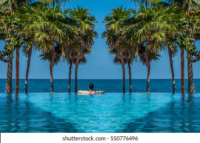 A Man Relaxing In An Infinity Pool Overlooking The Caribbean Sea.