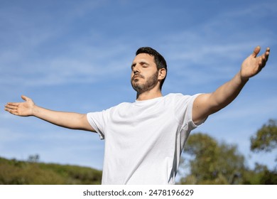 Man relaxing meditating and breathing in nature. Young man with his arms open while breathing and enjoying the sun on a summer day. - Powered by Shutterstock