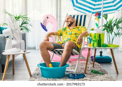 Man Relaxing On A Deckchair At Home In The Living Room, He Is Having A Staycation And Pretending He Is On A Beach