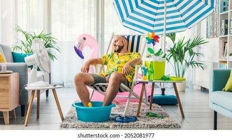 Man Relaxing On A Deckchair At Home In The Living Room, He Is Having A Staycation And Pretending He Is On A Beach