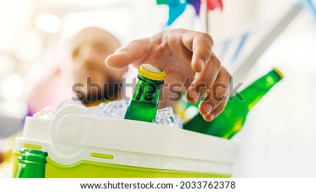 Man relaxing on a deckchair and taking a fresh beer from a cooler box, hand close up, selective focus