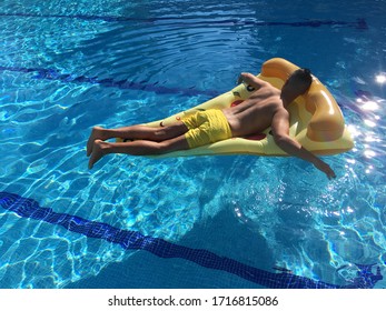 Man Relaxing On A Pizza Float In Swimming Pool. Enjoying The Time.