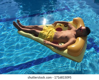 Man Relaxing On A Pizza Float In Swimming Pool. Enjoying The Time.