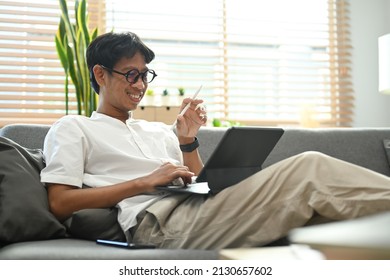 Man Relaxing On Sofa At Home And Browsing Internet With Laptop Computer.