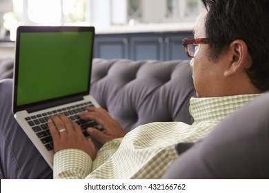 Man Relaxing On Sofa At Home Using Green Screen Laptop