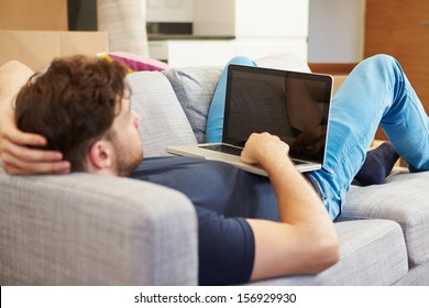 Man Relaxing On Sofa With Laptop In New Home