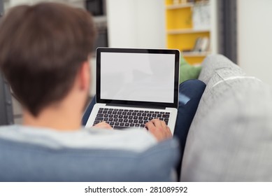 Man Relaxing On Sofa With Laptop Computer, Perspective View Of Over Shoulder Looking From Behind At Blank Screen