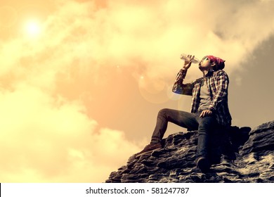 Man Relaxing On Top Of The Mountain And Drinking Bottled Water