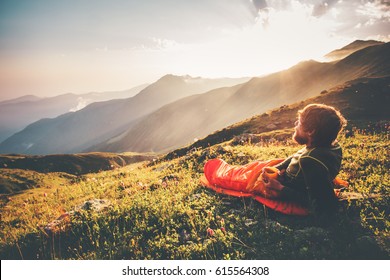 Man relaxing in sleeping bag enjoying sunset mountains landscape Travel Lifestyle camping concept adventure summer vacations outdoor hiking mountaineering harmony with nature