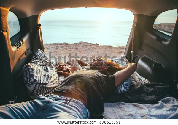 Man relaxing and\
sleeping inside car trunk. Fall trip in sunset. Freedom travel\
concept. Autumn weekend.