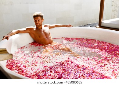 Man Relaxing In Spa Bath. Beautiful Handsome Healthy Male With Sexy Body Bathing, Bathe In Tropical Flower Petals Outdoor Tub, Enjoying Summer Aroma Therapy Beauty Treatment In Day Spa Salon. Relax