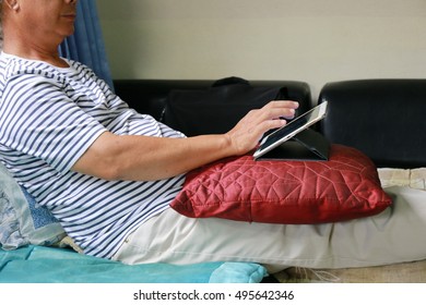 man relaxing using tablet on sofa.