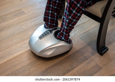 A Man Relaxing While Having A Foot Massage On A Machine At Home.