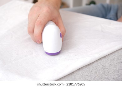 The man removes fabric pills using lint shaver. - Shutterstock ID 2181776205