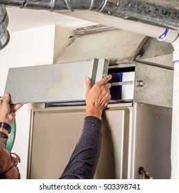 Man Removes The Furnace Filter Cover To Inspect