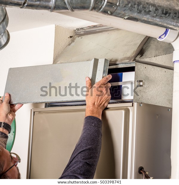 Man removes\
the furnace filter cover to\
inspect