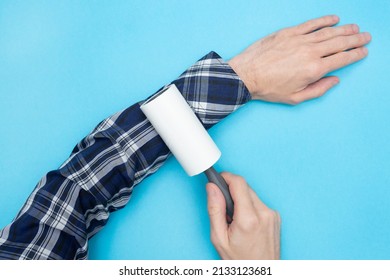 Man Removes Hair And Wool From Clothes With Lint Rollers. Lint Roller Dog, Cat, Animal, Hair Remover. Pet Fur, Fuzz. Blue Background. Flat Lay. Top View.