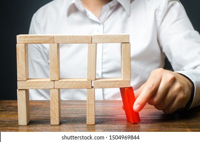 The man removes the red structural element, which will collapse. Incompetent businessman. Loss of key elements and employees. Damage to the opponent. Destruction of a complex structure by negligence.