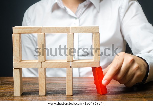 The man removes the red structural element,\
which will collapse. Incompetent businessman. Loss of key elements\
and employees. Damage to the opponent. Destruction of a complex\
structure by negligence.