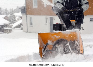 A man removes snow in winter. A man clears snow with a snow cutter