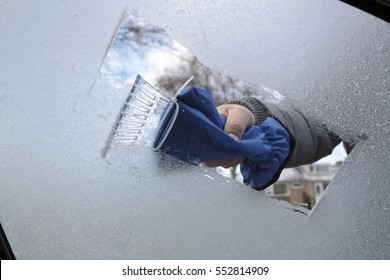 Man Removing Ice And Snow From A Car Window With A Ice Scraper
