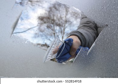 Man Removing Ice And Snow From A Car Window With A Ice Scraper
