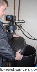 Man removing lid from brine tank, water softener unit.