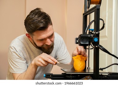 Man removing, scraping,  extra plastic parts from 3d printed object 