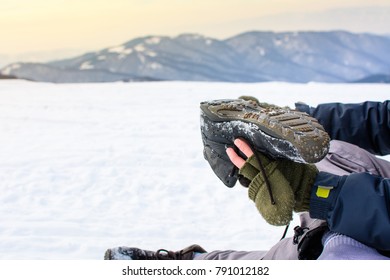 Man Removing Snow From His Shoe On A Winter Hiking Trip