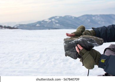 Man Removing Snow From His Winter Boot On A Mountain