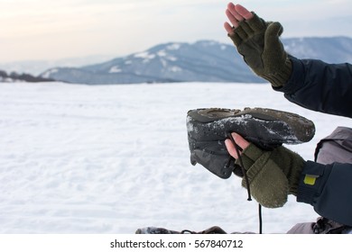 Man Removing Snow From His Winter Boot On A Mountain