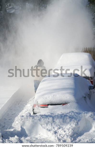 man removing snow on the driveway of the house by\
snow blower