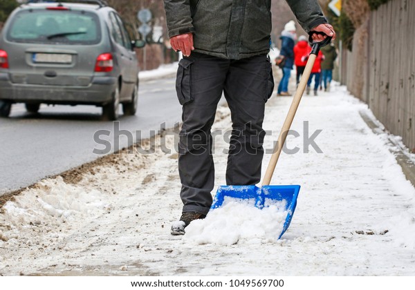 Man\
removing snow from the sidewalk after\
snowstorm.