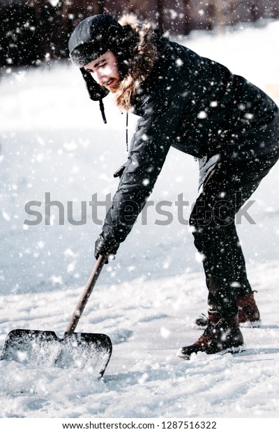 Man removing\
snow from sidewalk after\
snowfall.